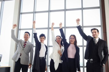 Beş neşeli iş adamının portresi, bir grup iş adamı ve iş kadını başarıyı, takım çalışmasının iş birliği gücünü kutlamak için el kaldırıyor..
