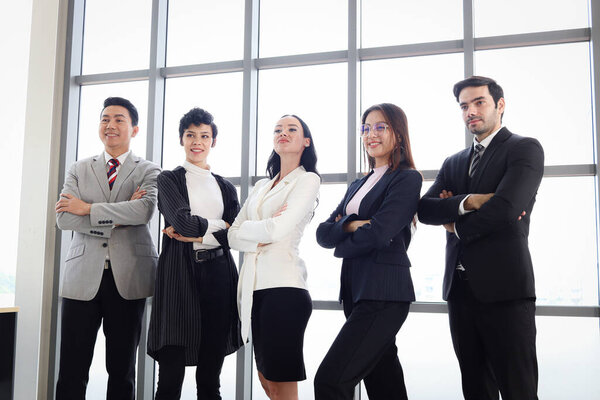 Portrait of five happy smiling businesspeople, group of businessmen and businesswomen confident standing with arms crossed, business team at modern office. Team collaboration and power of teamwork.
