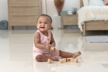 Evde, yatak odasında yerde otururken oyuncak oynayan, gülümseyen Afrikalı şirin bebek portresi. Çocuk ve mutlu çocukluk