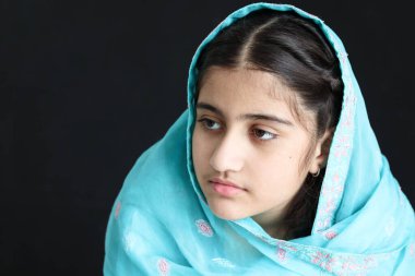 Hindistan 'da gülümseyen mutlu Hintli Müslüman kız çocuğunun portresi. Geleneksel elbise siyah arka planda başörtüsü takıyor. Mavi kostümlü güzel gözlü kız çocuğu..