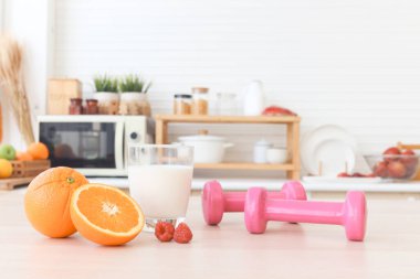 Dambıllar, portakal meyvesi, ahududu, ahşap masa üzerinde bulanık mutfak arka planlı süt. Kilo vermek için sağlıklı yiyecekler ve egzersizler. Proteinli yiyecekler, kalsiyum, vitaminler ve spor.