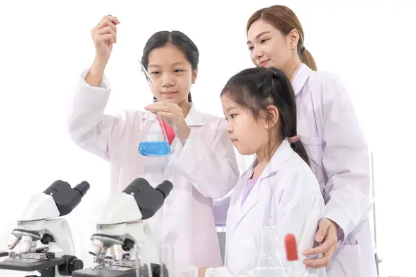 Two happy young scientist girls in lab coat use lab equipment for study in school laboratory. Asian female teacher teaches schoolgirl children to do science experiments. Kid learning science education