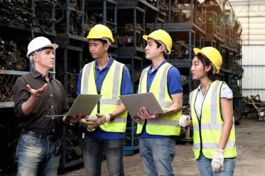 Güvenlik yeleği ve miğferi olan endüstriyel kadın ve erkek işçi ustabaşını dinleyin, fabrika fabrikasında birlikte çalışmak için tartışın. Sektör işyerinde çalışan profesyonel mühendis ekibi.