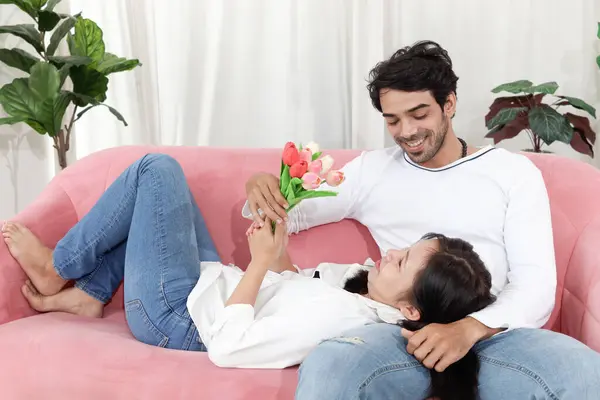 一对快乐的夫妇在客厅里 女人躺在男朋友的腿上 而他却坐在沙发上 在一起共度时光和在家中共度浪漫时光的时候放松爱人的爱 图库图片