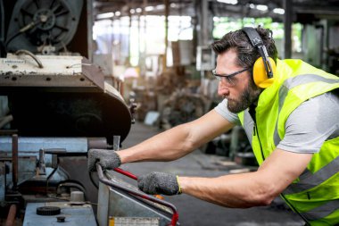 Fabrika fabrikasındaki motor denetimi sırasında kask ve güvenlik yeleği giyen erkek endüstriyel mühendis. İşçi endüstri işyerinde makine ile çalışan.