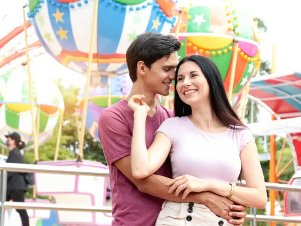 Genç çift yaz tatilinde lunaparkta birbirlerine sarılırlar. Genç ve güzel bir sevgili birlikte takılıyor, lunaparkta romantik randevuları var. Eğlence parkındaki neşeli gençler..