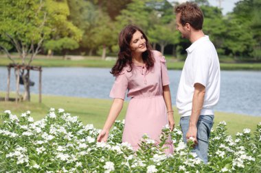 Mutlu güzel çift çiçek bahçesinde birlikte vakit geçirmeyi seviyor. Neşeli aşıklar parkta rahatlıyor. Kadın ve erkeğin güneşli bir günde dışarıda romantik bir randevusu var..