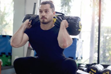 Güçlü genç kaslı adam spor salonunda ağırlık kaldırıyor. Formda egzersiz yapan yakışıklı bir sporcu. Atletik ağırlık çalışması, sağlıklı ve mükemmel vücut geliştirme programı..