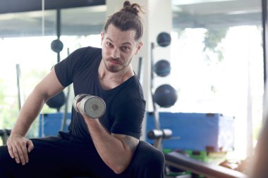 Spor salonunda halteri kaldıran güçlü, genç, kaslı bir adam. Yakışıklı sporcu spor salonunda halter egzersizi yapıyor. Atletik ağırlık çalışması, sağlıklı ve mükemmel vücut geliştirme programı.