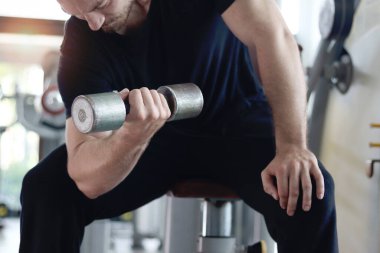 Spor salonunda halteri kaldıran güçlü, genç, kaslı bir adam. Spor adamı spor salonunda halter egzersizi yapıyor. Atletik ağırlık çalışması, sağlıklı ve mükemmel vücut geliştirme programı.