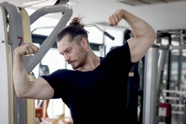 Gururlu güçlü bir adamın portresi spor salonunda egzersiz yaparken mükemmel kaslarını gösteriyor. Spor kaslı adam spor salonunda egzersiz yapıyor. Spor egzersizleri ve vücut geliştirme programları sağlıklı mükemmel vücut elde ediyor..