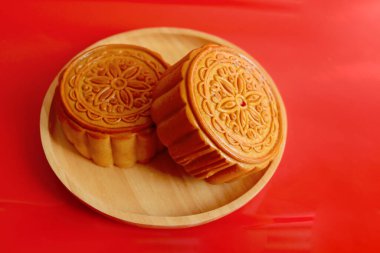 Ahşap tabakta ay çöreği, kırmızı arka planda Çin usulü ay çöreği. Sonbahar ortası kutlaması, Mutlu Çince çevirisi Sonbahar Festivali.