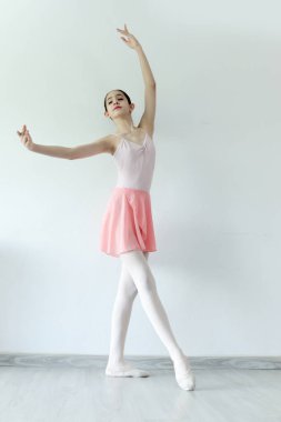Güzel genç balerin kız beyaz arka planda bale yapıyor. Esnek genç bale genç bayan dansçısı beyaz stüdyoda pratik yapıyor. Güzel kadın bale yapıyor..