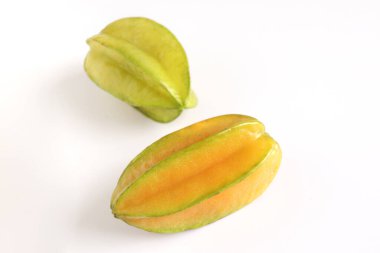 Beyaz arka planda iki olgun, sulu karambol yıldız meyvesi. Averrhoa carambola, yıldız elması, lezzetli tropikal meyve.