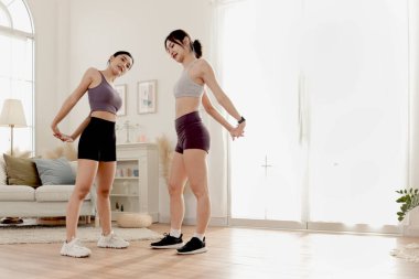 İki Asyalı kadın egzersiz yapmadan önce vücutlarını esnetiyorlar. Neşeli spor kankası kadınlar evde arkadaşlarıyla spor yapıyor. Sportif kız antrenörle egzersiz yapar. Sağlıklı spor hobi yaşam tarzı. 