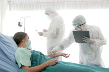 Enfeksiyon kapmış hasta için hastalık tedavi odası. İki uzman doktorla yatakta yatan hasta kadın için. Koruyucu giysiler giyen doktor hastanedeki karantinadaki hastalarla ilgilenir..