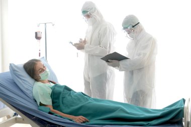 Enfeksiyon kapmış hasta için hastalık tedavi odası. İki uzman doktorla yatakta yatan hasta kadın için. Koruyucu giysiler giyen doktor hastanedeki karantinadaki hastalarla ilgilenir..