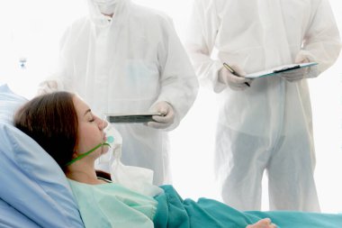 Enfeksiyon kapmış hasta için hastalık tedavi odası. İki uzman doktorla yatakta yatan hasta kadın için. Koruyucu giysiler giyen doktor hastanedeki karantinadaki hastalarla ilgilenir..