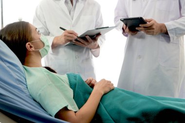 Enfeksiyon kapmış hasta için hastalık tedavi odası. Ameliyat maskesi takan hasta iki uzman doktorla aynı yatakta yatıyor. Doktor, hastanedeki karantina odasındaki hastalarla ilgilenin..