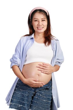 Mutlu gülümseyen Asyalı hamile kadının portresi. Beyaz arka planda karnı soyutlanmış bir anne. Hamile anne karnına hafifçe dokunuyor. Koca göbekli hamile bir kadın. Mutlu aile