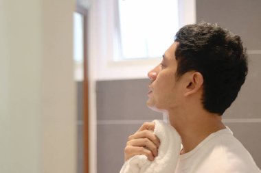 Asyalı adam banyo lavabosunda yüzünü yıkadıktan sonra havluyla siliyor. Bir adam sabah onun yüz bakımı yüzünü temizliyor. Erkek tıraş olur ve yüzünü yıkar.. 