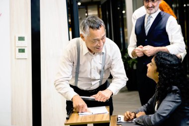 İş adamları sıra halinde konferans kayıt masasına geliyorlar. Asyalı kıdemli izleyiciler ve diğerleri resepsiyona kayıt olmak için sıraya girdiler. Katılımcılar seminer toplantısına katılmadan önce bilgileri doldururlar