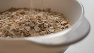 Kuru taneler bir tabağa dökülür ve bir kaydırak oluşturur. Hızlı ve sağlıklı bir kahvaltı hazırlama süreci.