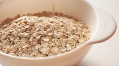 Yulaf ezmesi taneleri çabucak yulaf lapası demleme kabına düşer. Beyaz bir kaseyi demlenmeden önce yavaş yavaş kuru tanelerle doldur..