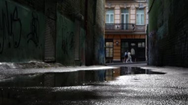 Duvarlarında grafiti olan eski, pis bir bahçe. Arka planda, yoğun trafiğin olduğu bir caddeye doğru bir kemer görebilirsiniz..