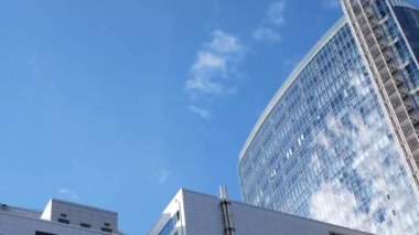 Metropolis 'teki ofis kompleksinin arkasında büyüyen yeşil çimlerin vurulması. Video bulutsuz bir yaz gökyüzünü yakalıyor..