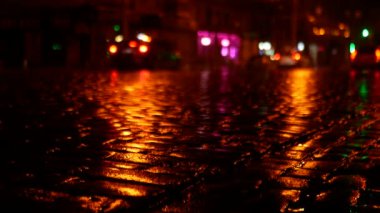 Biraz yağmurdan sonra kaldırım taşları parlak ve parlak oldu. Arabalar geceleri sokaklarda koşuşturuyor..