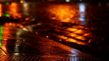 Geceleri yağmurdan sonra kaldırım taşlarından aşağı su akar. Islak yol farklı renkte parıldıyor..