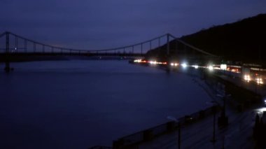 Dinyeper ve Trukhanov Adası 'na giden yaya köprüsünün çekimleri. Yanıp sönen farlar uzaktaki nehir kıyısını çerçeveliyor..