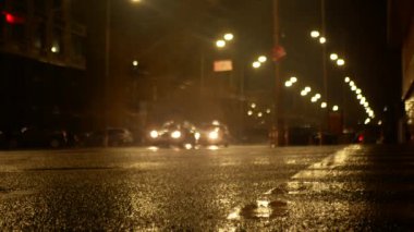 Gece yağmurdan sonra büyük bir şehrin gece caddesi. Asfalt seviyesinde ateş ediliyor. Çerçevede bir sürü araba var..