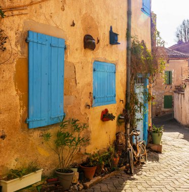 Lautrec köyünde, Tarn, Occitanie, Fransa 'da bir evin sarı duvarına doğru bisiklet sürün.