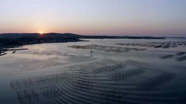 Thau lagünündeki masaların yanında bir istiridye balıkçı teknesi. Arka planda Sete var.