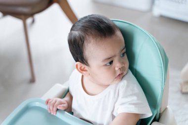 Portre Bebek yüksek sandalyedeki bir şeye bak..