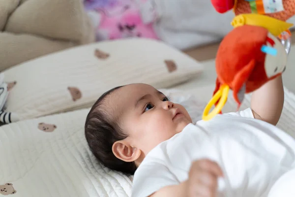 Bebek yatakta oyuncaklarla oynamayı sever..