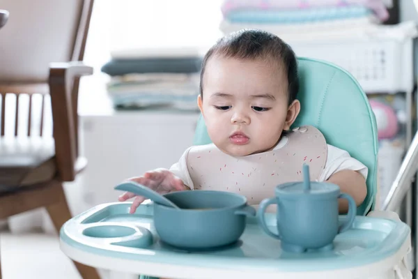 Bebek yüksek sandalyede yulaf lapası yiyip eğleniyor..