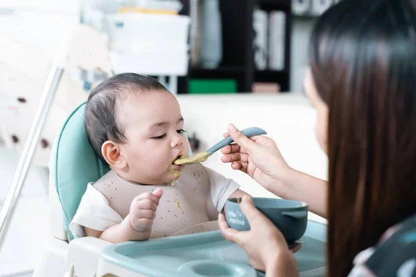 Bebek yüksek sandalyede yulaf lapası yiyip eğleniyor..