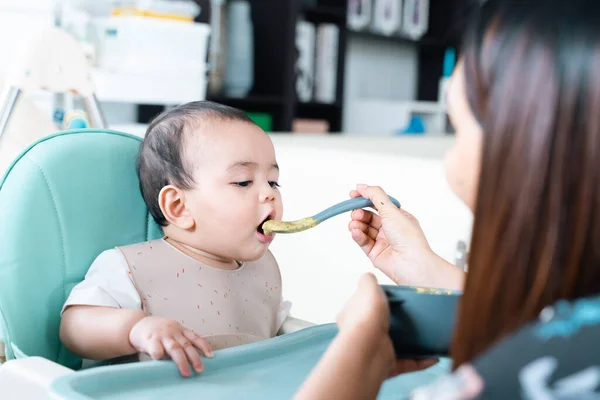 Bebek yüksek sandalyede yulaf lapası yiyip eğleniyor..