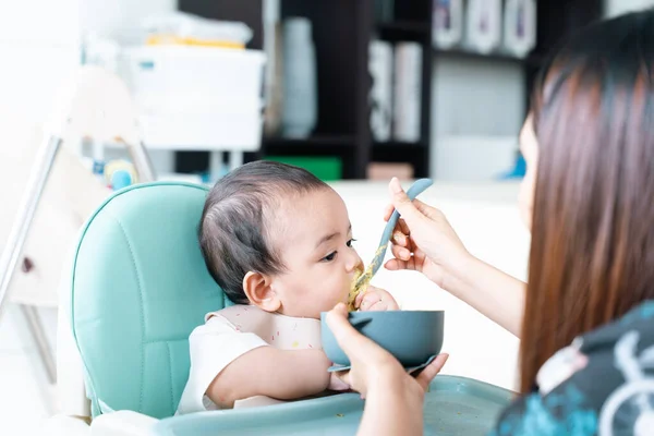 Bebek yüksek sandalyede yulaf lapası yiyip eğleniyor..