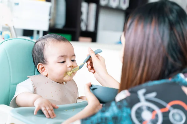 Bebek yüksek sandalyede yulaf lapası yiyip eğleniyor..