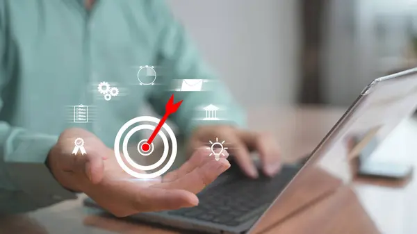 Bilgisayara dijital hedef simgesi yerleştiren işadamı, hedef belirleme, stratejik yön ve performans hedefi kavramı.