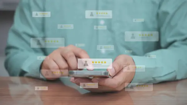 İş adamı eli, çevrimiçi anket, müşteri geribildirimi, hizmet değerlendirmesi ve memnuniyet puanlarını temsil eden 5.0 etiketli saydam bir derecelendirme çubuğuna işaret ediyor..