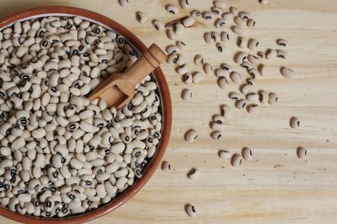 Tahta masadaki kasede pişmemiş siyah göz bezelyeleri.