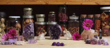 Amethyst Crystals and Flowers On Meditation Table With Jars of Dried Herbs in Background