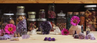 Amethyst Crystals and Flowers On Meditation Table With Jars of Dried Herbs in Background