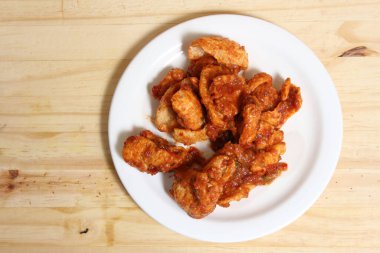 Tabakta kırmızı salsa soslu kızarmış domuz derisi.