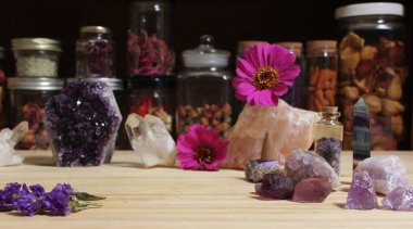 Amethyst Crystals and Flowers On Meditation Table With Jars of Dried Herbs in Background